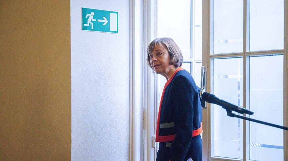 Frau geht an einem grünen Schild "Notausgang" vorbei