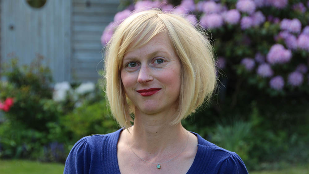 Eine blonde Frau lächelt in die Kamera