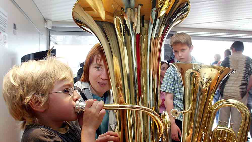 Kleiner Junge bläst in eine Tuba