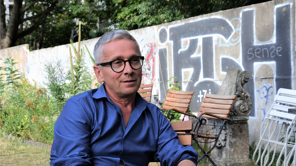 Bernd Schumann im garten Niemandsland mit Teilen der ehemaligen Mauer