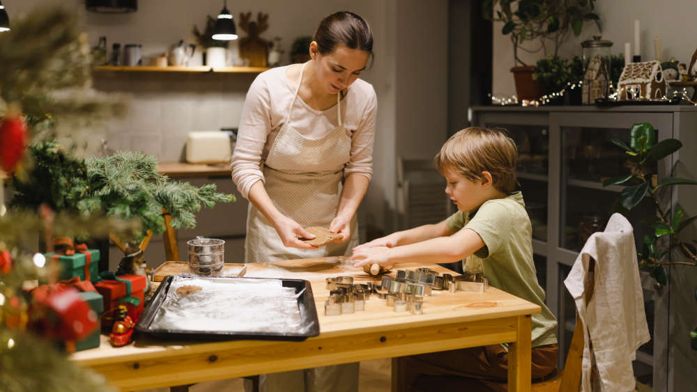 Mutter und Sohn backen Weihnachtsplätzchen in der geschmückten Küche