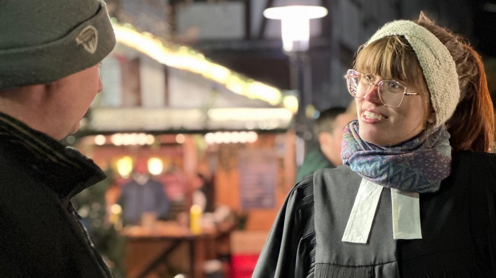 Pastorin Louisa Pandera spricht mit einem Besucher auf dem Weihnachtsmarkt von Burgdorf.