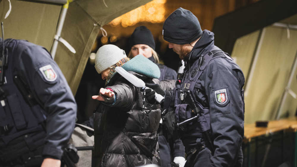 Polizisten durchsuchen Besucher in Zelten, die neben Kölner Dom stehen