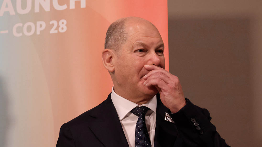 Mann mit Glatze und schwarzem Anzug fasst sich an den Mund