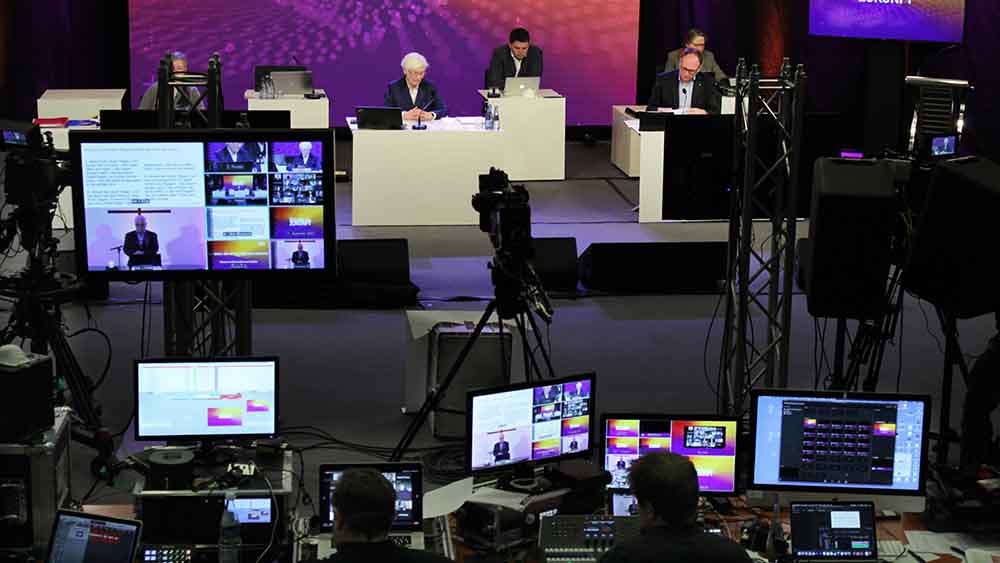Mehrere Menschen sitzen in einem Regieraum an Monitoren, im Hintergrund ein großes Pult