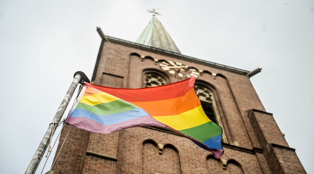 Regenbogenfahne weht vor einer Kirche (Symbolbild)