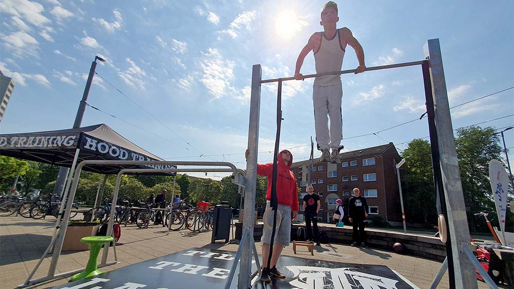 Daniel Magel leitet beim Outdoor-Training in der Bremer Vahr das Hood Training an und sichert Kinder und Jugendliche, die sich an Reckstangen und Ringen ausprobieren wollen