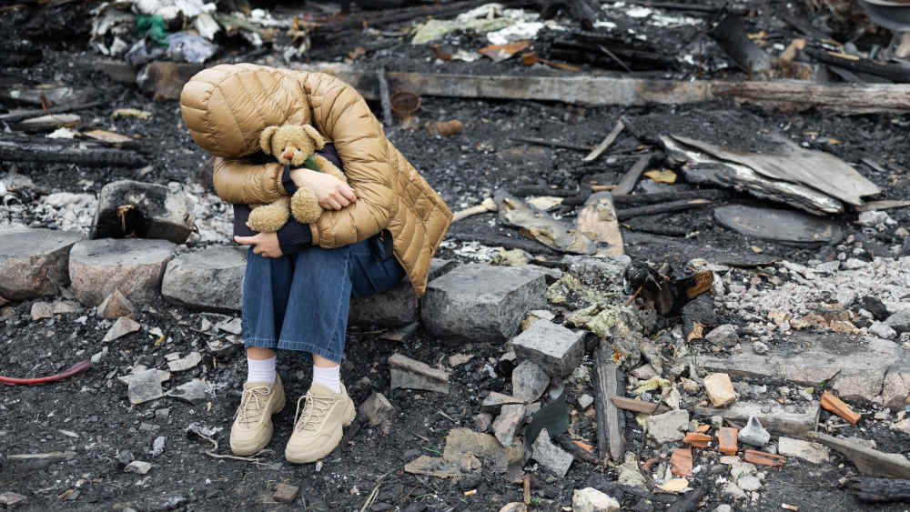 Ukrainisches Mädchen sitzt vor den Ruinen ihres zerstörten Hauses (Archivbild)