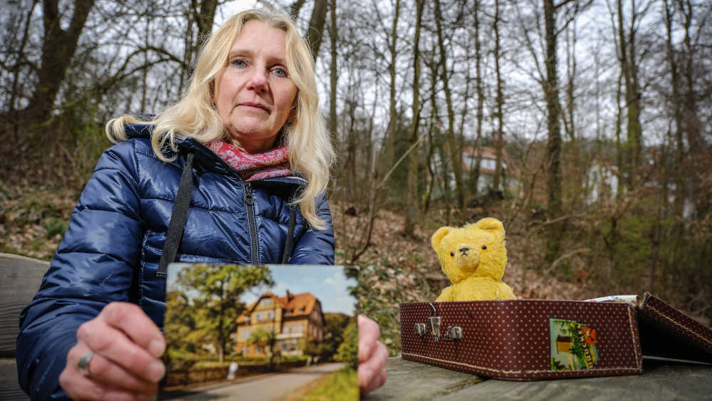 Sabine Schwemm mit einer Postkarte vom Waldhaus und ihrem "Kinderkoffer" 