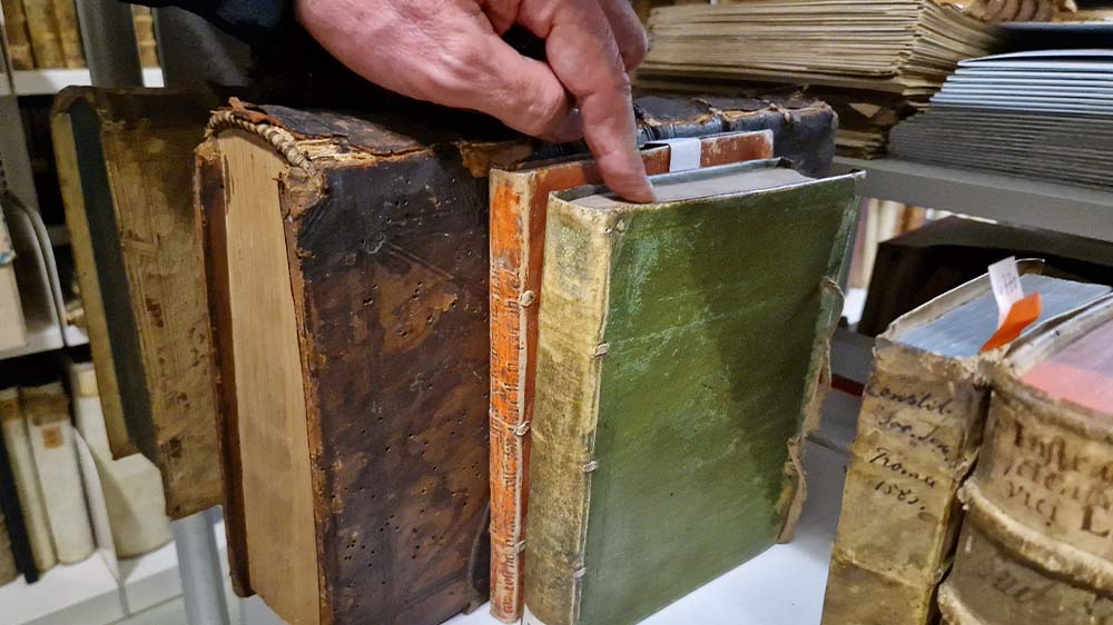 Armin Schlechter zeigt ein Buch mit grünem Einband aus dem Bestand der Pfaelzischen Landesbibliothek, das arsenbelastet ist 