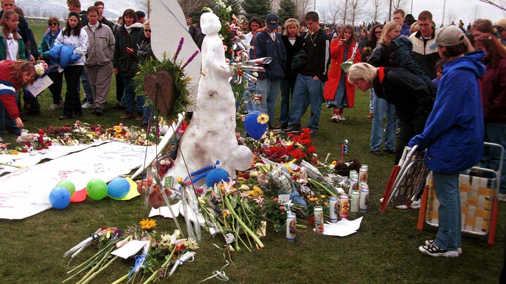 Menschen legen Blumen nieder an einem Engel aus Schnee in Gedenken an das Schulmassaker in der Columbine Highschool in Littleton (Archivbild aus 1999)