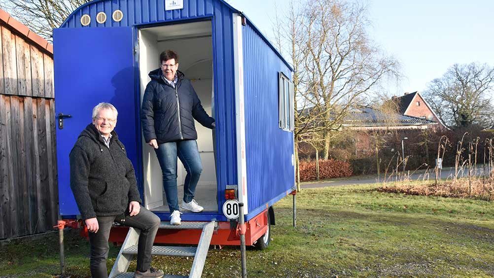 Pastor Andreas Hellmich und Kirchenvorsteherin Elke Wiebusch vor der mobilen Kirche.