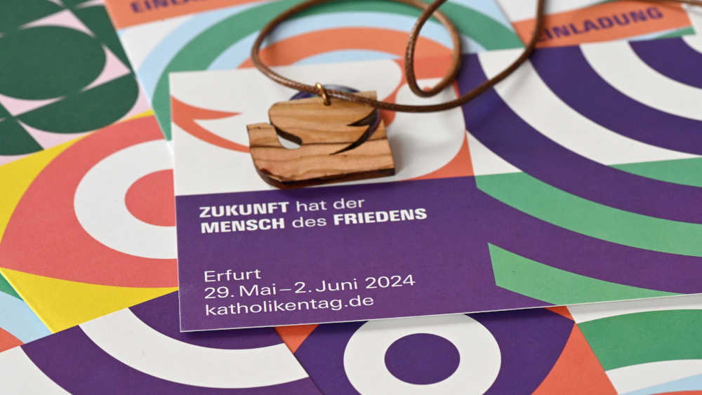 Postkarten und eine Friedenstaube aus Holz zum Umhängen des 103. Deutschen Katholikentags 2024