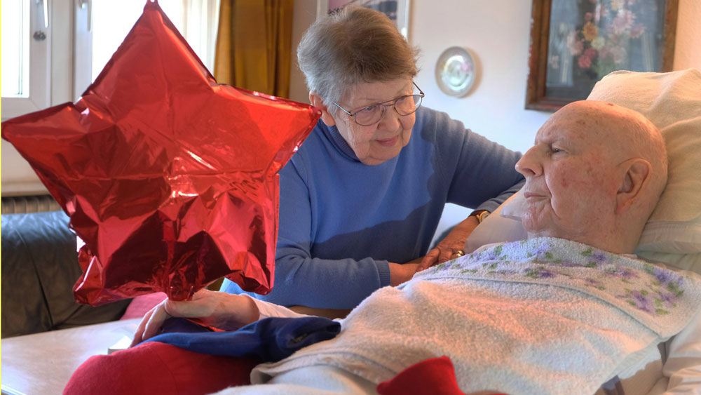 Frau pflegt ihren demenzkranken Mann.