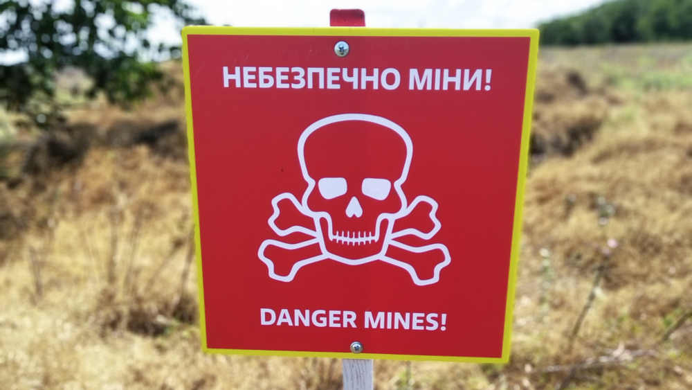 Ein Schild warnt vor Landminen auf einem Feld in der Ukraine