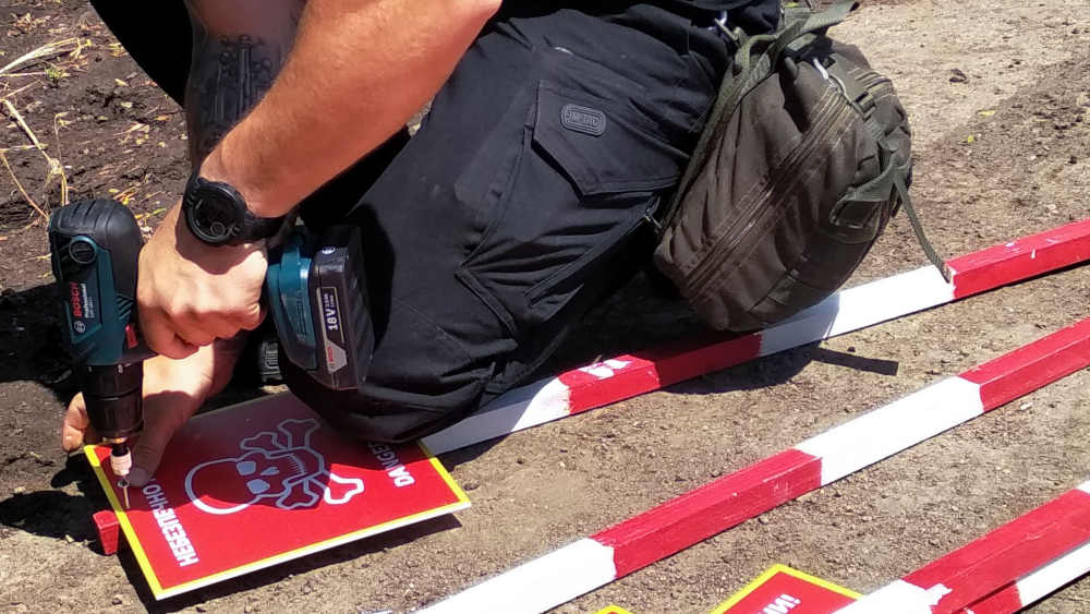 Warnschilder, die vor Landminen auf Feldern in der Ukraine warnen, werden an Stäbe befestigt