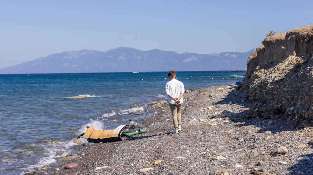 Anna-Nicole Heinrich, Synodenpräses der Evangelischen Kirche in Deutschland (EKD), betrachtet Reste eines Schlauchbootes am Strand von Kos