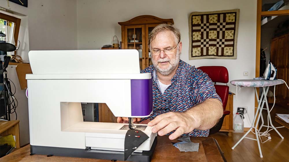 Pfarrer Jörg Seiter der Michaelisgemeinde Blankenloch in seiner Wohnung beim Zusammennähen von Stoffteilen
