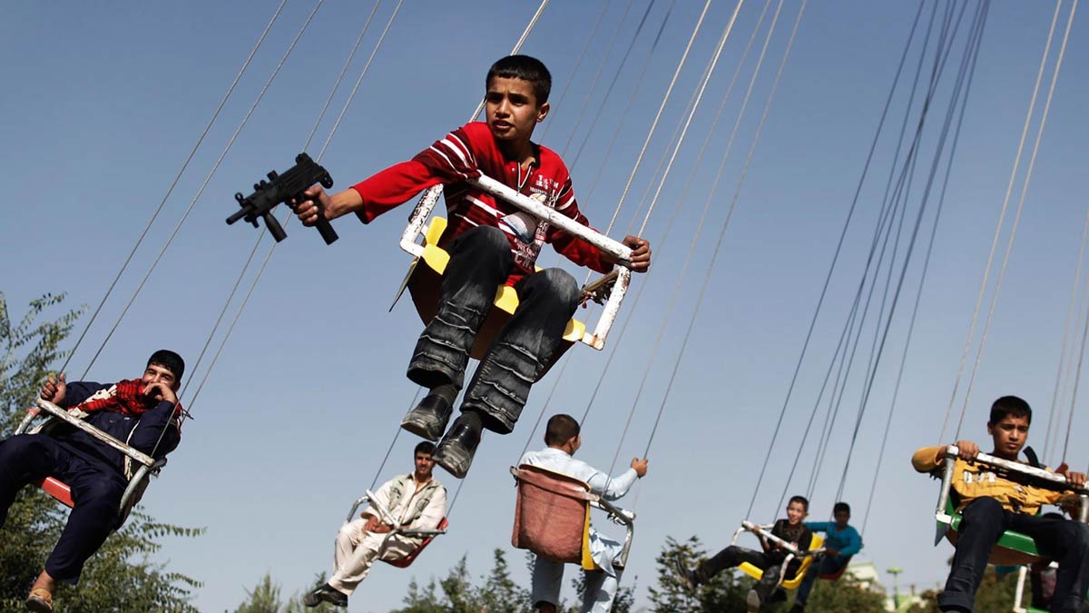 Ein afghanischer Junge hält ein Spielzeuggewehr, während er in Kabul Karussell fährt.