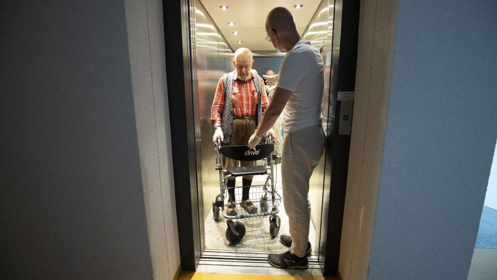 Altenpfleger und Mann mit Rollator in einem Aufzug. Nach Angaben der Bagso sind derzeit nur 1,5 Prozent der Wohnungen barrierefrei