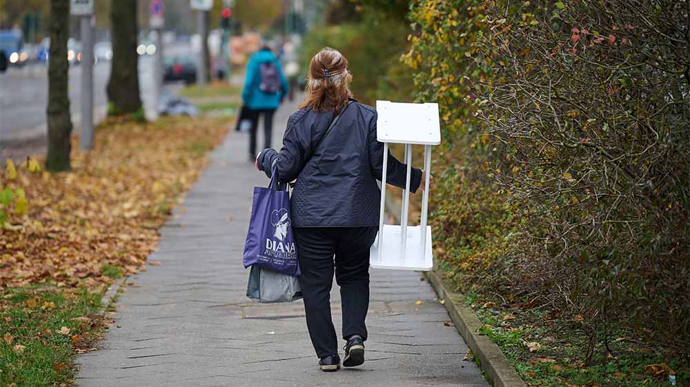 Hat sich gelohnt: Eine Frau trägt ein gebrauchtes Regal aus dem Sozialkaufhaus