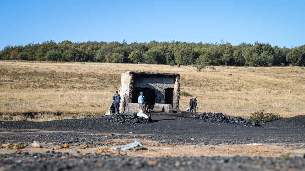 Kleinbergbauarbeiter vor einer verlassenen Mine