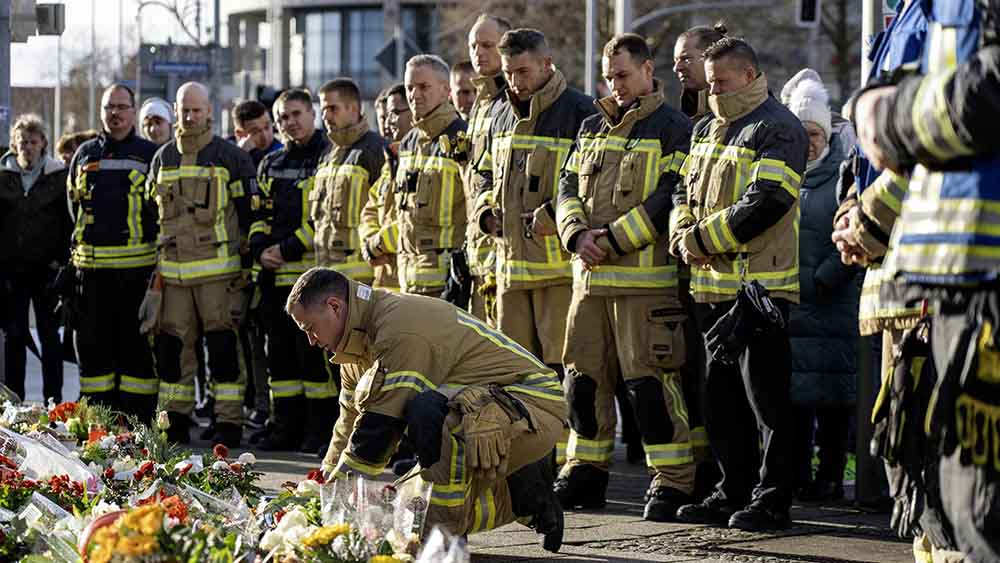 An der Magdeburger Johanniskirche legen Feuerwehrleute Blumen nieder