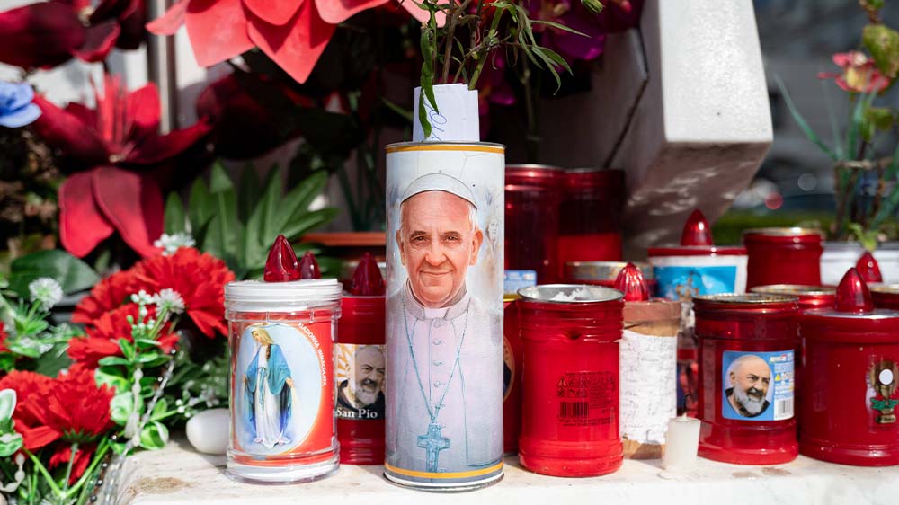 Kerzen werden zu Füßen einer Statue von Papst Johannes Paul II. vor dem Gemelli-Krankenhaus aufgestellt