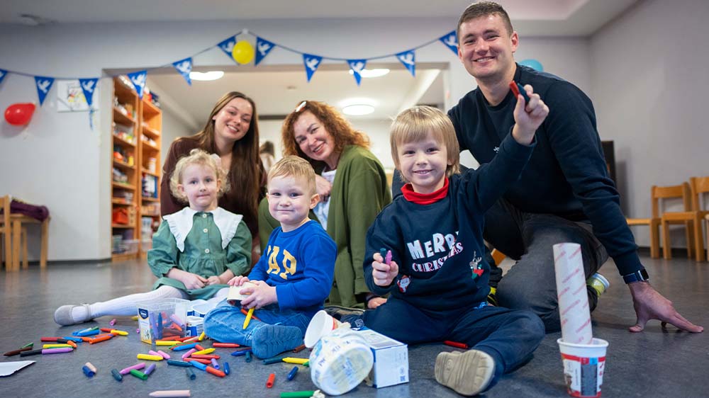 Erzieher Alisa Hniedo, Iryna Khudenko und Andrii Kazmirchuk (oben v.li.) mit den Kindern Emilia, Leon und Miron (unten v.li.) im Kindergarten des Ukrainischen Vereins Frankfurt