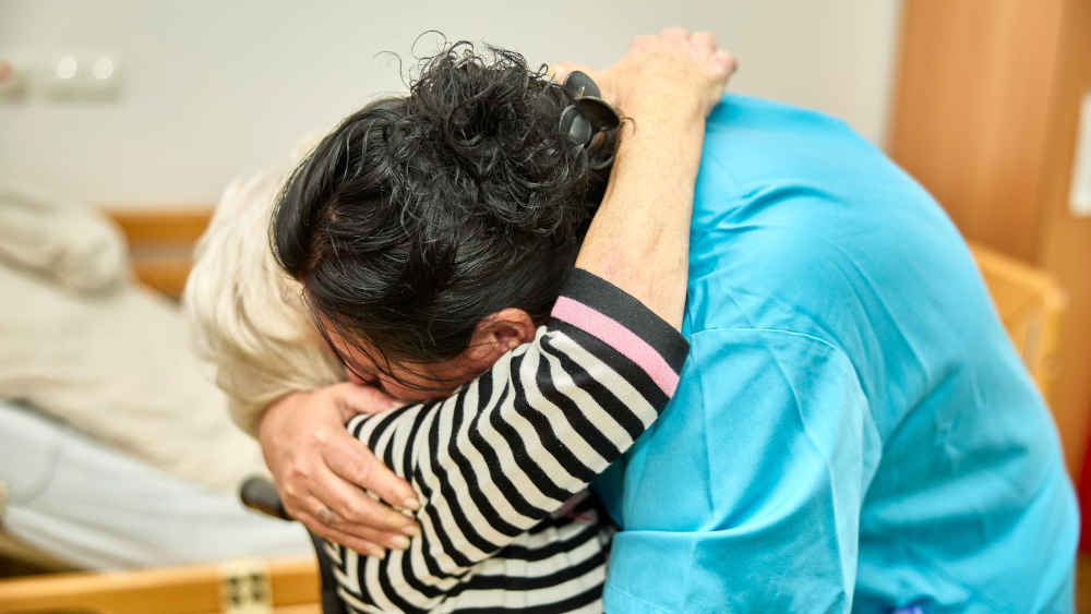 Ausländische Pflegekraft mit einer Bewohnerin in einem Pflegeheim