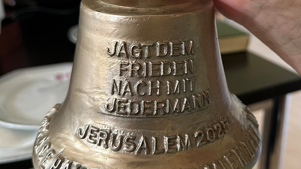 Eine Nachbildung der Friedenglocke in Form einer kleinen Handglocke. „Jaget dem Frieden nach“ ist in sie eingraviert