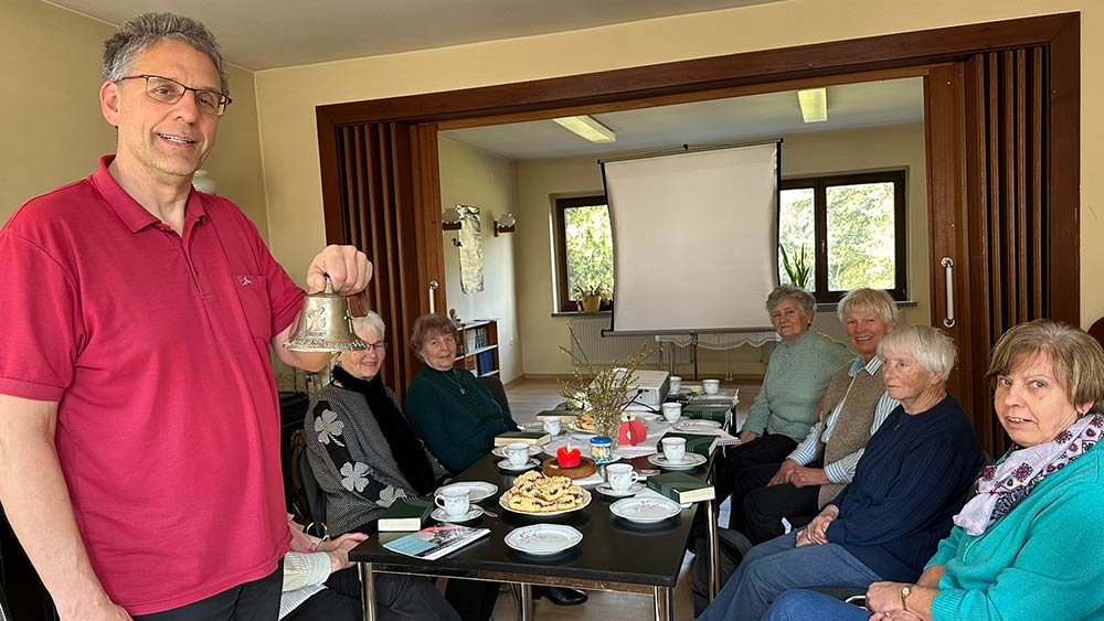 Pfarrer Helmut Kautz präsentiert an der Kaffeetafel in Meyenburg die Glockenreplik. Auf dem Treck wird sie die gemeinsamen Mahlzeiten ankündigen