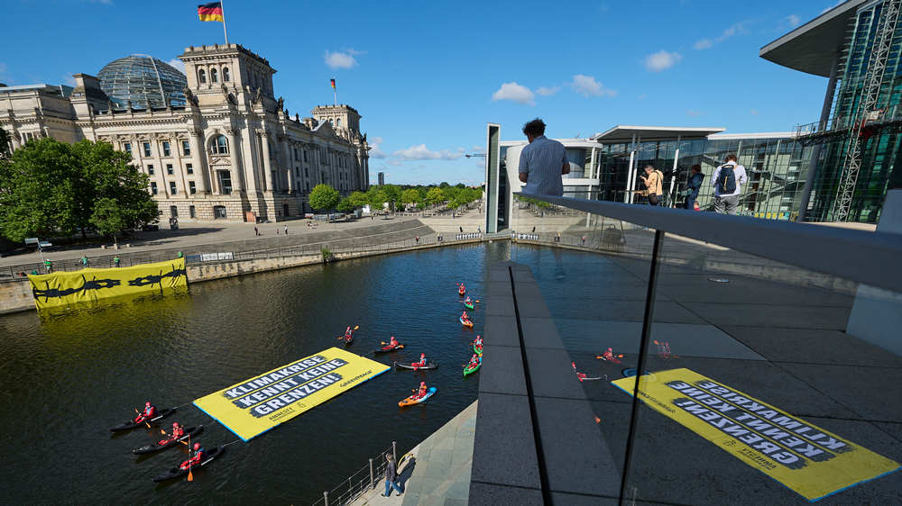 Mit einem Banner auf der Spree vor dem Reichstag machen Greenpeace und Amnesty auf den Weltflüchtlingstag aufmerksam