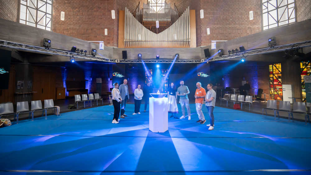 In der Mitte des sechseckigen Kirchenraums steht eine Schale, in der ein beleuchteter Wasserstrahl sprudelt. Dazu gibt es Musik und Videos auf sechs Bildschirmen