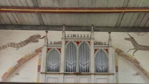Blick auf eine Orgel, links von dieser ist eine mittelalterliche Malerei einer Schlange. Rechts eine eines Einhorn