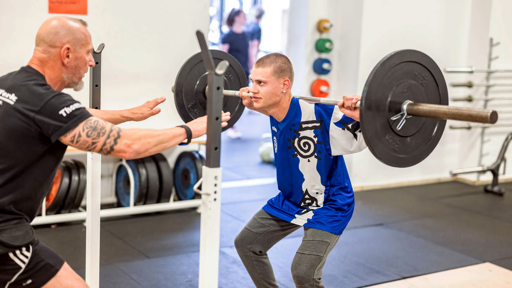 Heilerziehungspfleger Thomas Fraunholz (li.) spornt seine Schützlinge beim Gewichtheben an