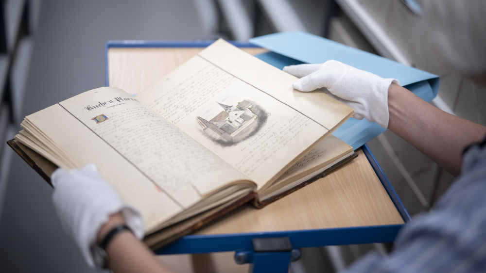 Eine Mitarbeiterin der hessen-nassauischen Landeskirche (EKHN) mit einer Pfarrchronik im EKHN-Zentralarchiv