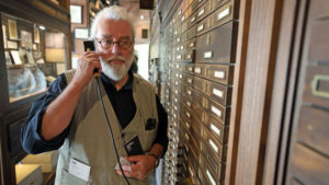 Älterer Mann mit Bart und Brille an einer Hörstation auf einem Schiff