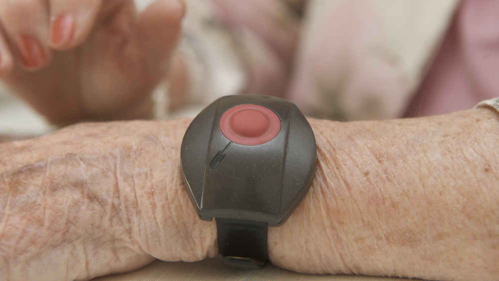Eine Seniorin mit Hausnotruf-Sender am Handgelenk 