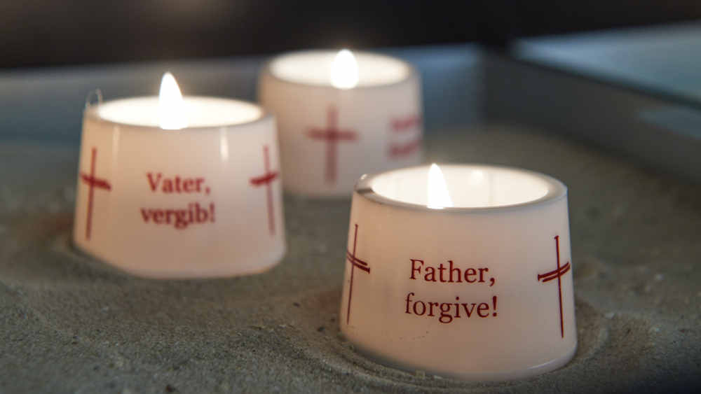 Fürbittkerzen in der Nagelkreuzkapelle der Kirche mit deutscher und englischer Aufschrift „Vater, vergib!“