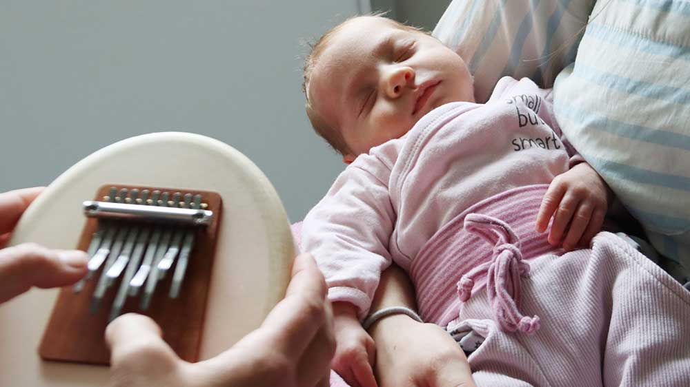 Musiktherapeutin Uta Jordan spielt Kalimba-Daumenklavier fuer Lotta, die mit nur 2.200 Gramm Gewicht zu früh auf die Welt kam