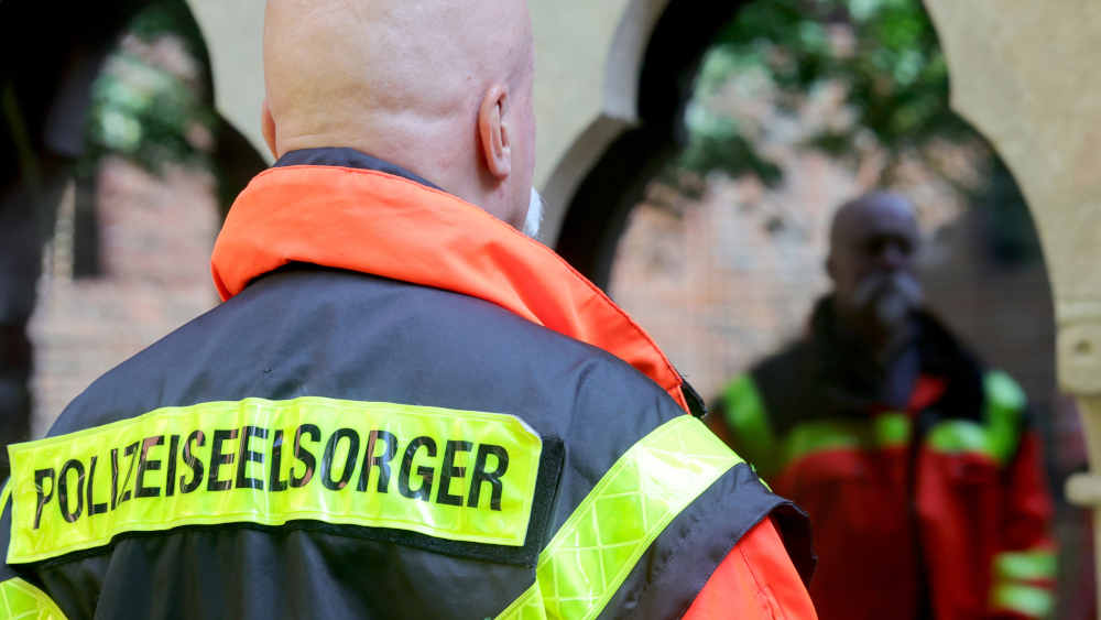 Die orangefarbene Weste mit der Aufschrift "Polizeiseelsorger" hängt immer griffbereit im Schrank