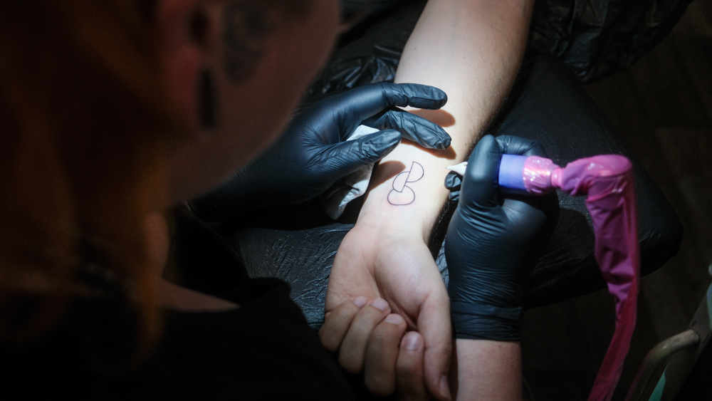 Eine Tätowiererin  sticht das Opt.Ink zur Organspende