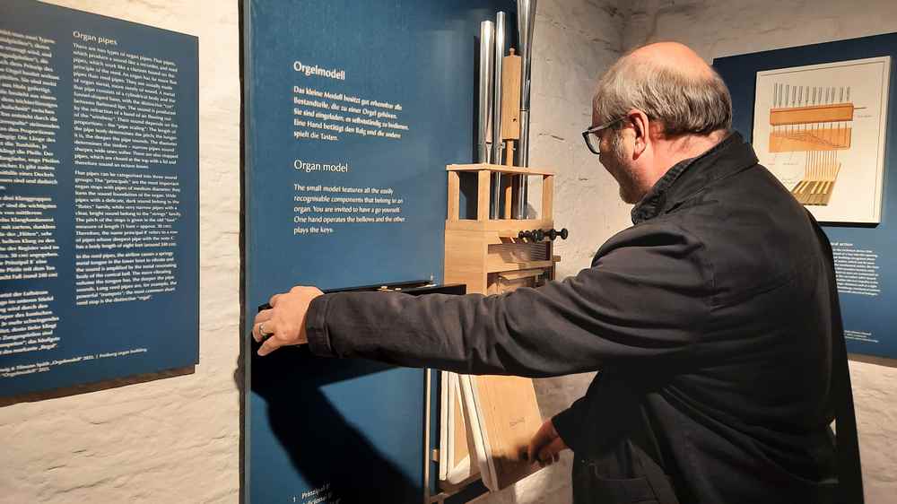 Pastor Karsten Struck führt eine Mini-Orgel der Ausstellung vor.