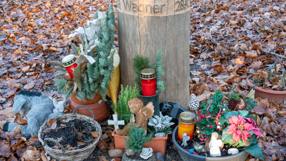 Blumen und Kerzen an einem Bestattungsbaum