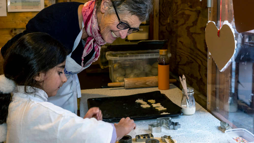 Die siebenjährige Liana und Anne Zwick, Mitglied vom Kinderschutzbund, beim Plätzchenbacken in der Weihnachtsbäckerei auf dem Weihnachtsmarkt in Speyer