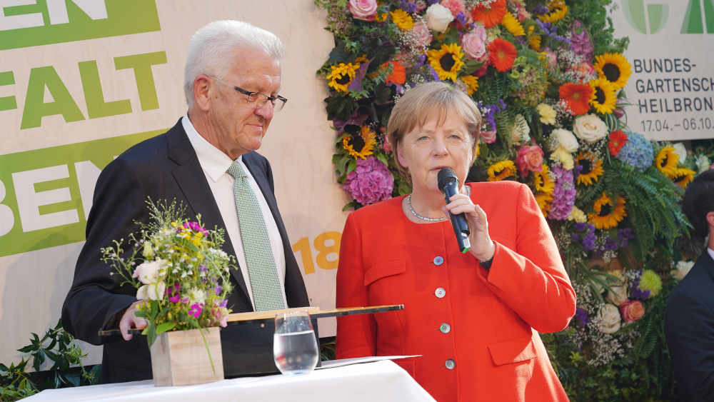 Angela Merkel wird für ihre Corona-Politik geehrt. Hier mit Winfried Kretschmann auf einer Sommerparty in Baden Württemberg (Archivbild von 2018)