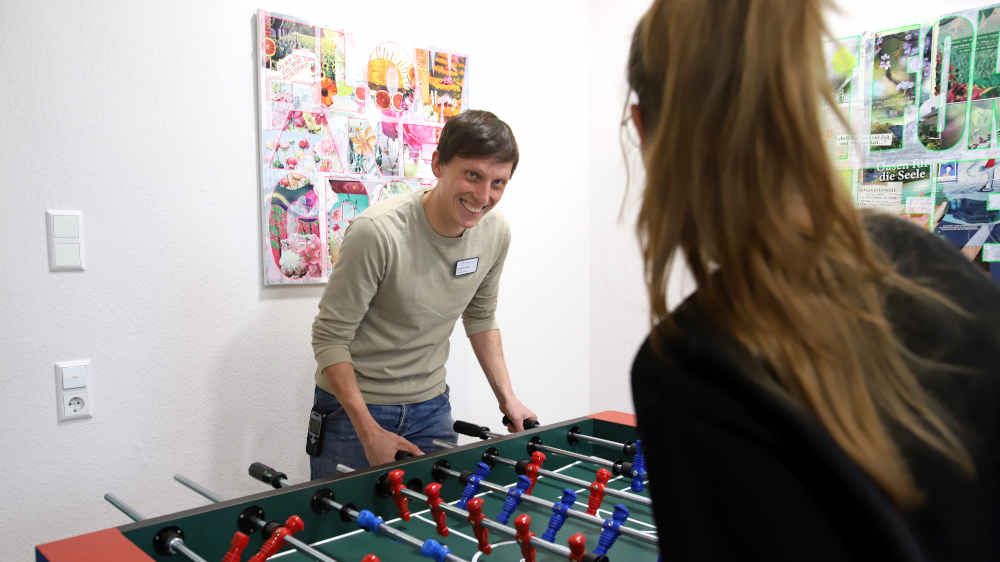 Therapeut Jonathan Roth (li) spielt mit einer jungen Patientin Tischfußball im Adoleszentenzentrum