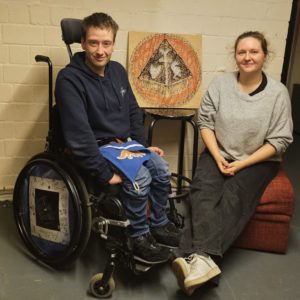 Ein junger Mann im Rollstuhl sitzt neben einer jungen Frau