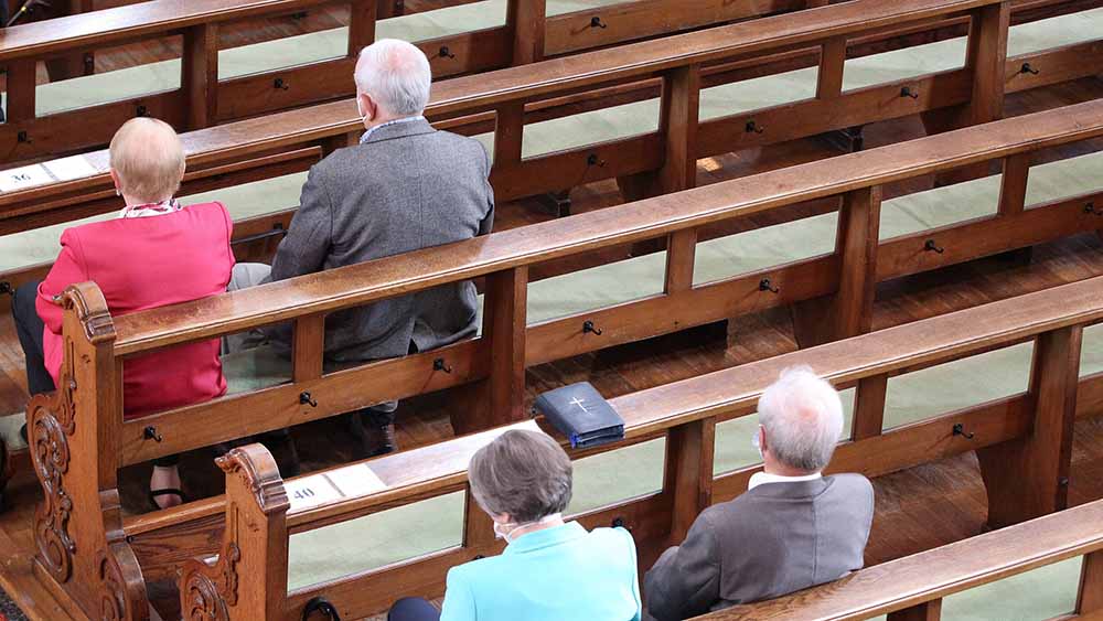 Menschen sitzen nebeneinander im Gottesdienst